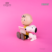 将图片加载到图库查看器，Statuina di Charlie Brown e Snoopy che leggono un foglio.
