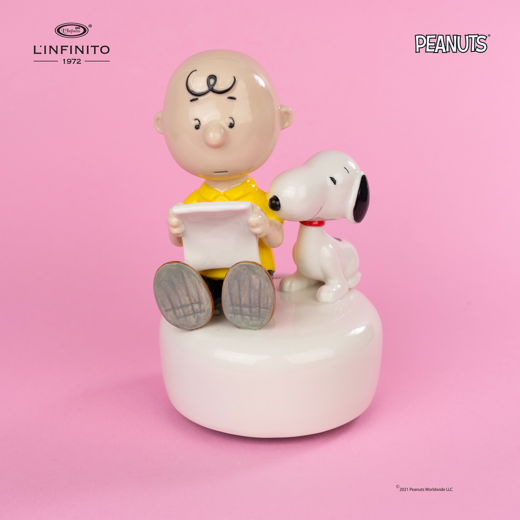 Statuina di Charlie Brown e Snoopy che leggono un foglio, su carillon musicale